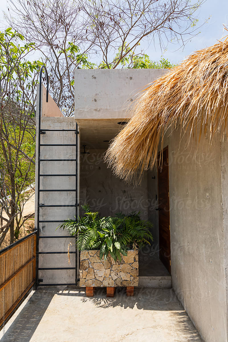 A concrete beach house with palm tree roof