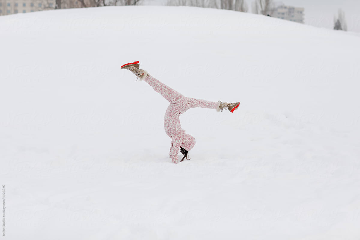 Beautiful woman doing splits in the snow wearing onesie