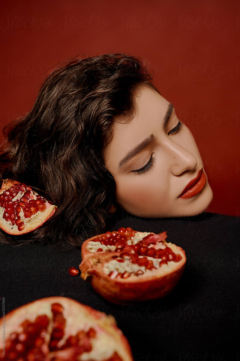 beauty woman on a red background holds  pomegranate