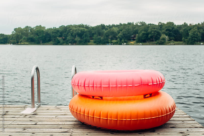 Pink and orange tubes on a raft by a lake