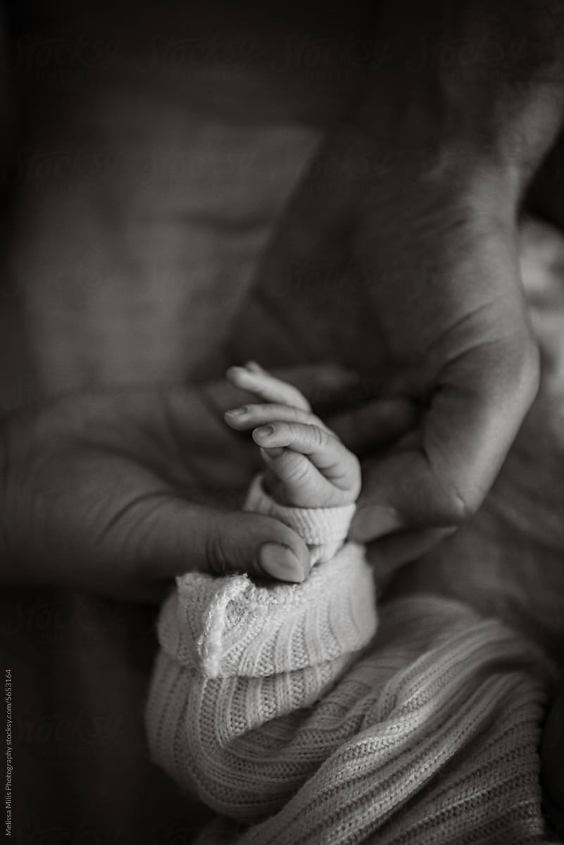 monochrome image of newborn and parents hands