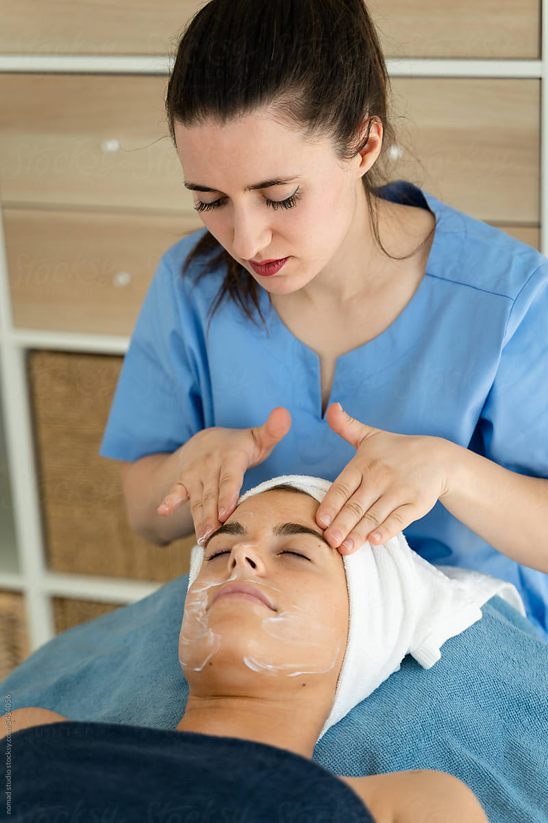 Woman relaxes under the care of an esthetician at a spa.