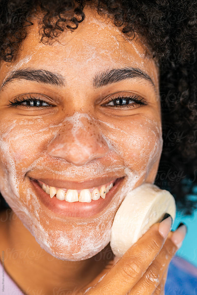 Hispanic woman cleansing face with handmade soap