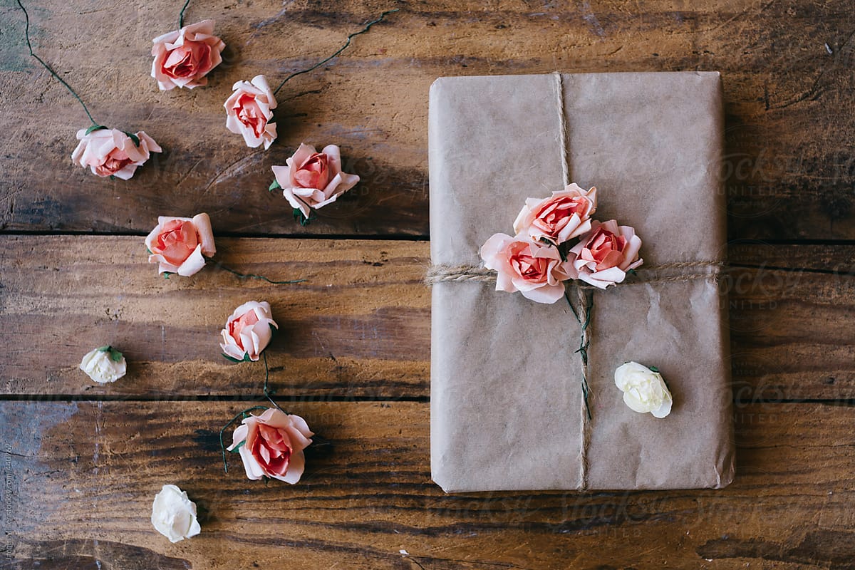 Gift wrapped in brown paper and decorated with pink flowers made from paper