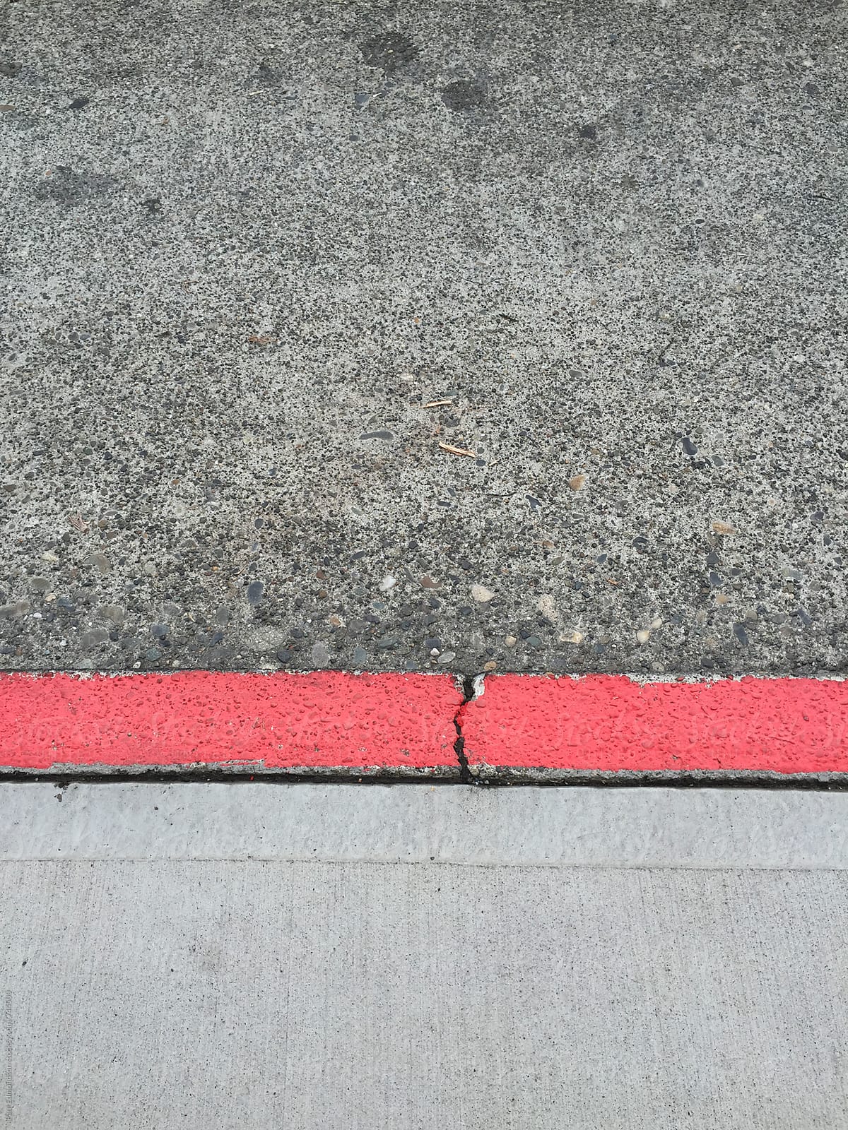 Painted red curb along urban sidewalk and street