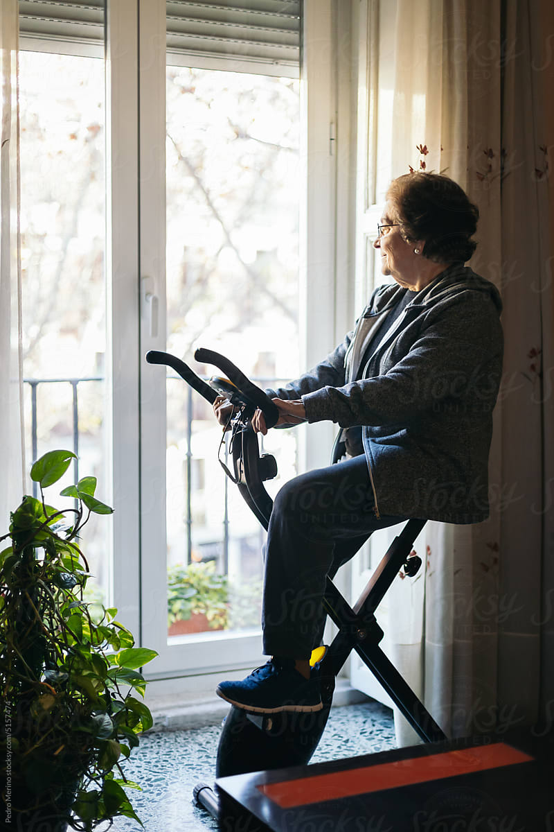 Senior Woman Exercising On Cycling Machine At Home