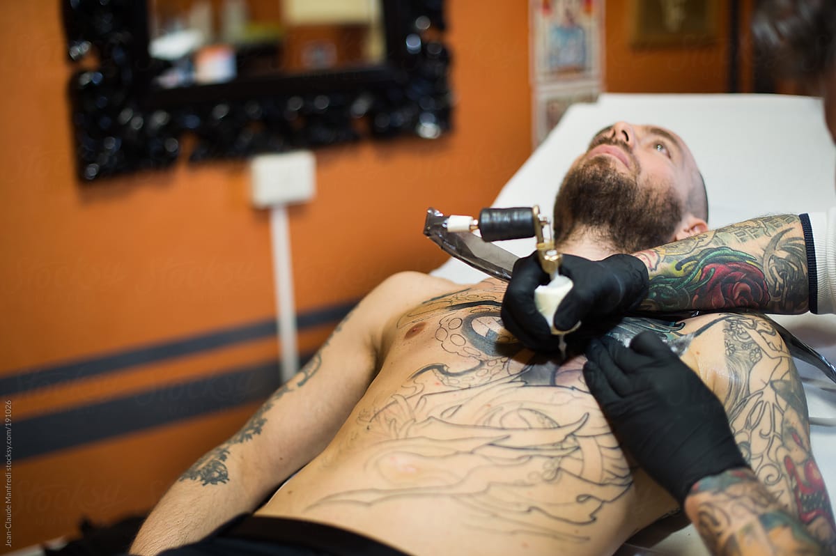 Making Tattoo: a man continue his work in progress tattoo on his chest