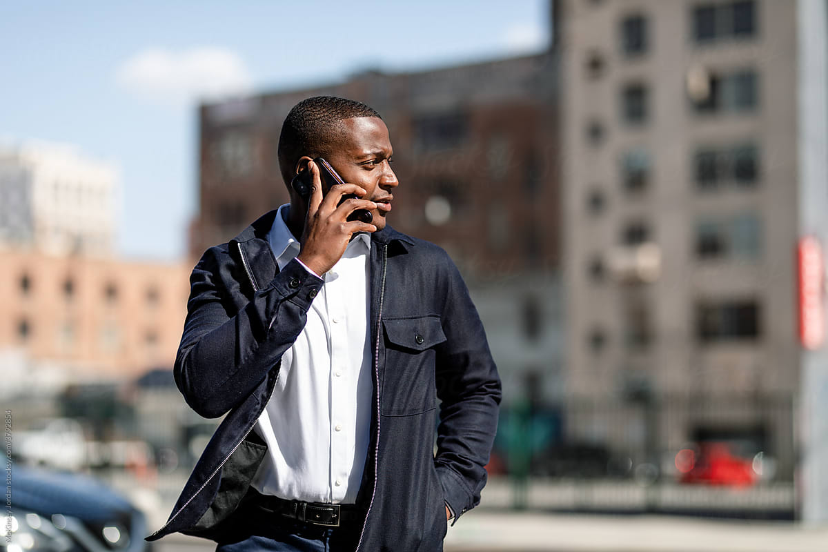Businessman Walks Through a City While Talking on His Phone