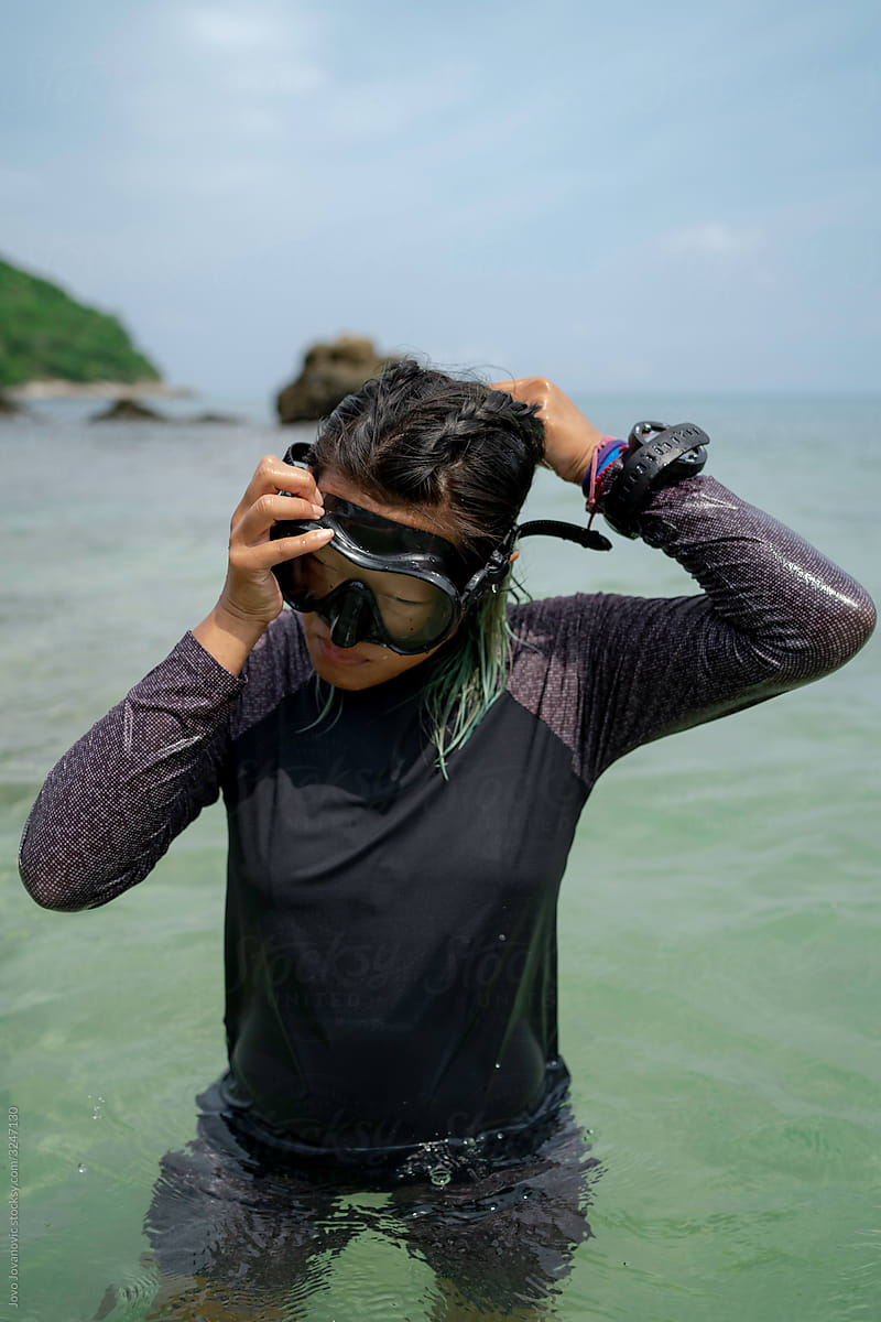 Female diver adjusting mask on head standing in ocean