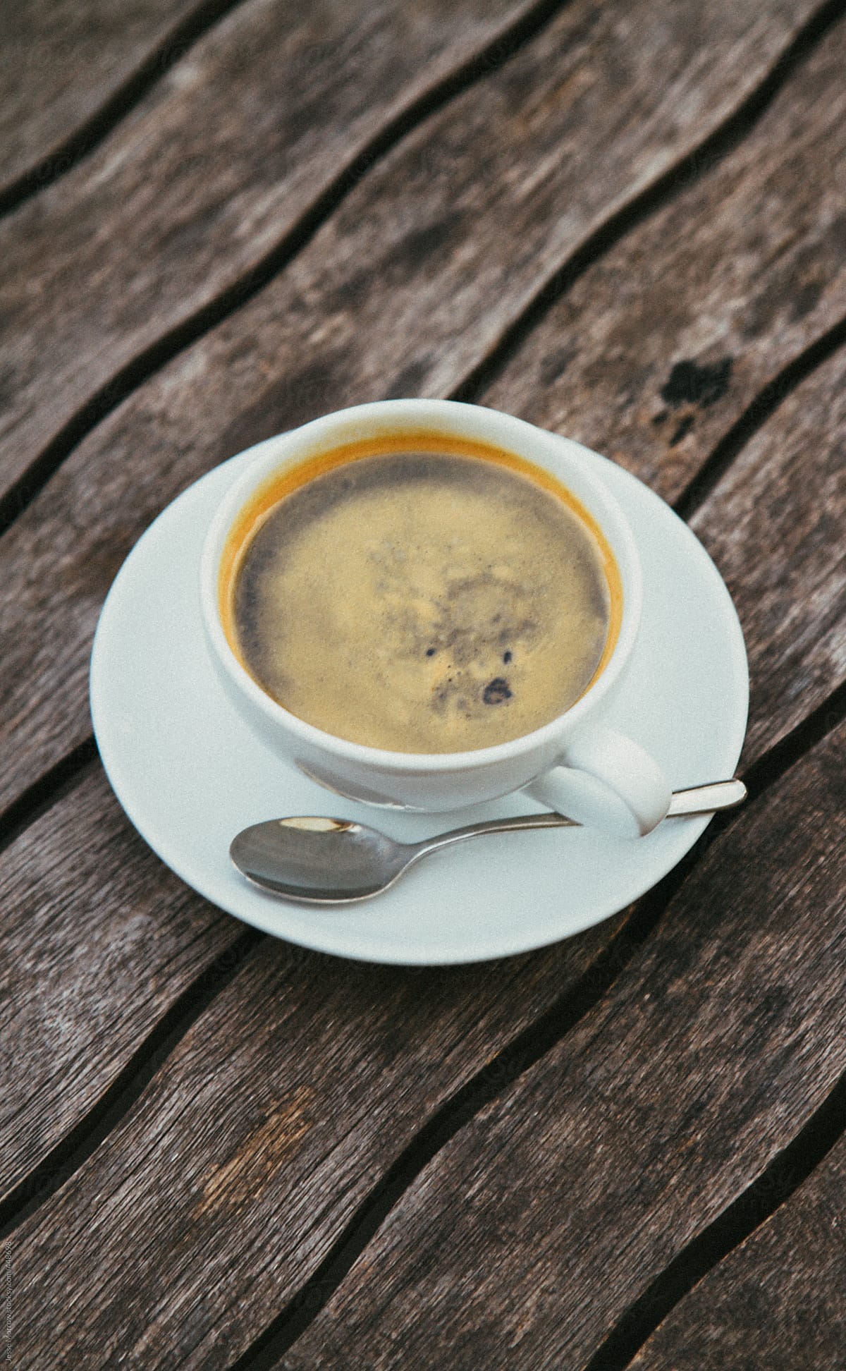 Coffee in white mug and saucer on old wooden table
