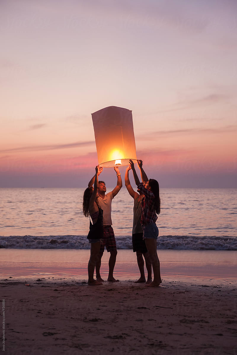 Group Of Friends Releasing A Lantern Outside At The Beach By Jovo Jovanovic 