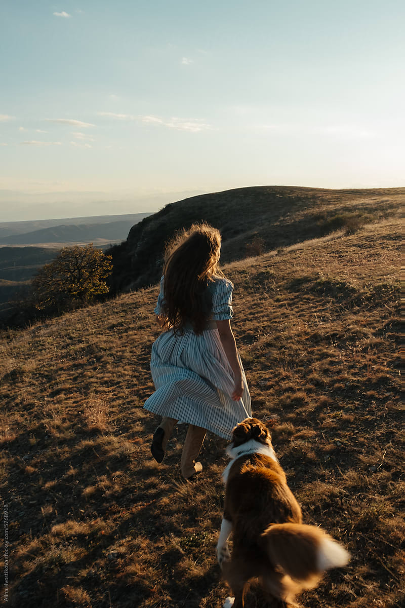 Happy woman running with Border Collie dog in the mountains