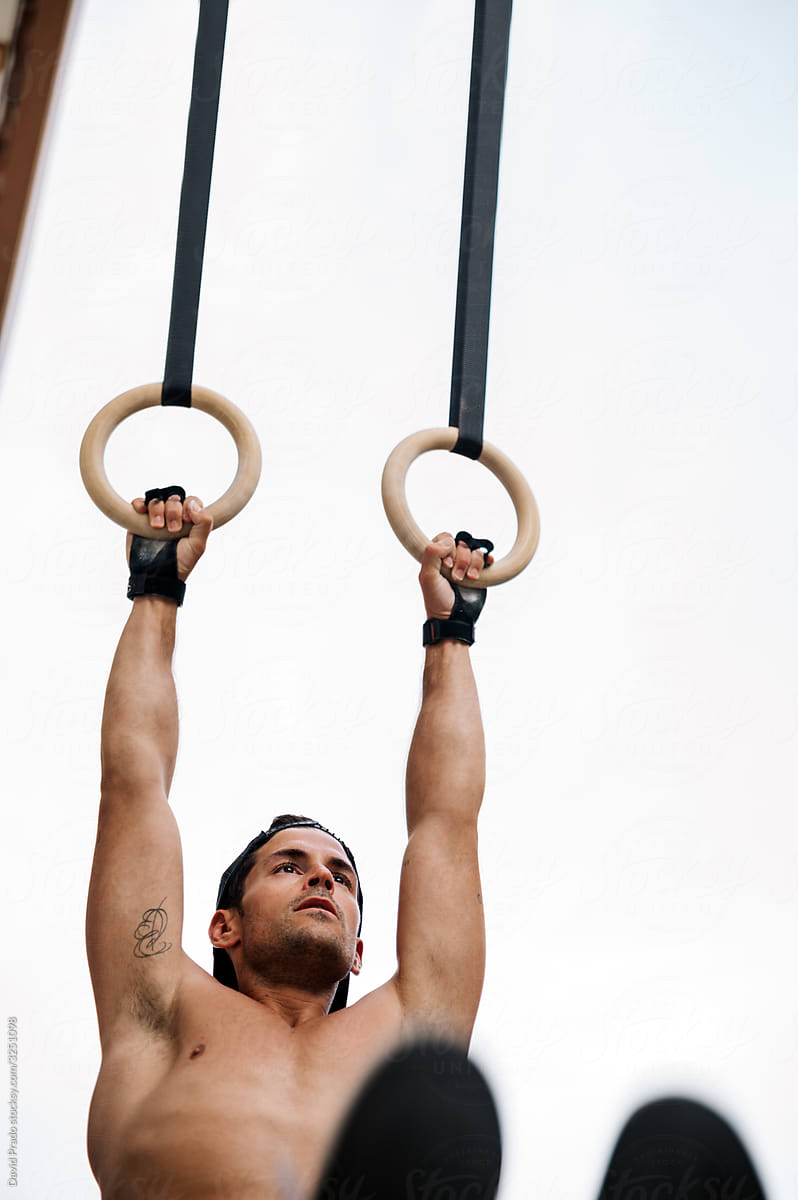 Muscular athlete performing exercise with gymnastic rings