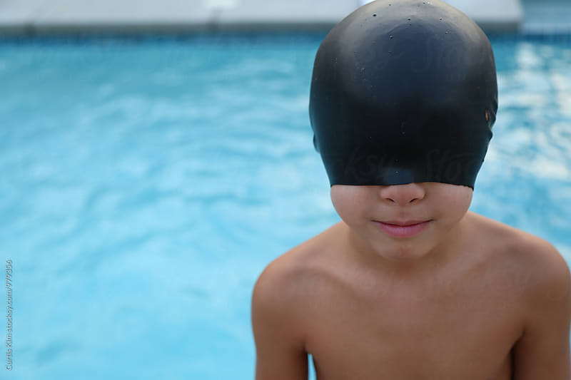 Young boy with swimming cap over his eyes