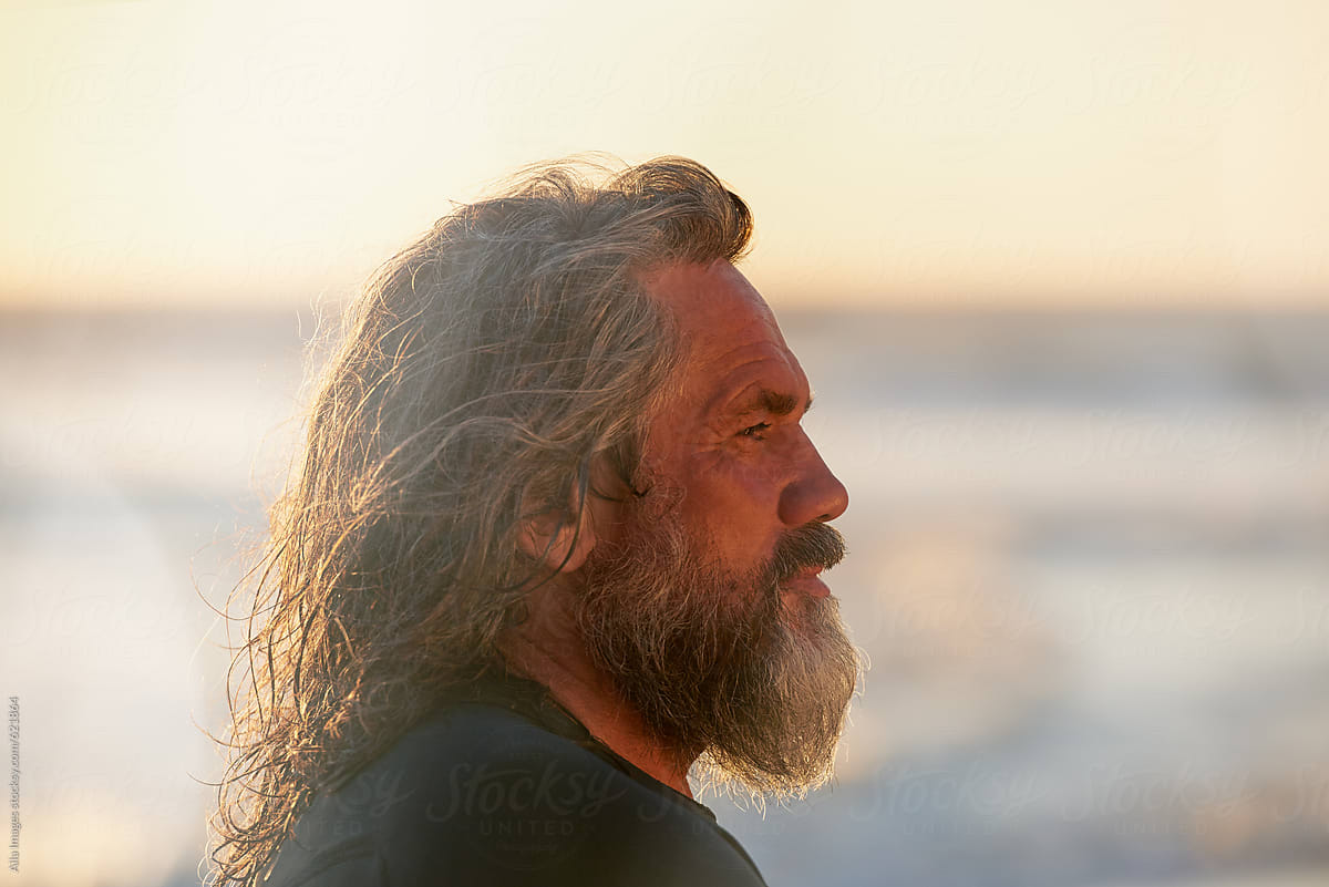 Profile portrait of old surfer at sunset