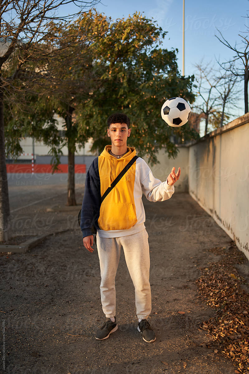 Serious man with soccer ball standing on sports ground