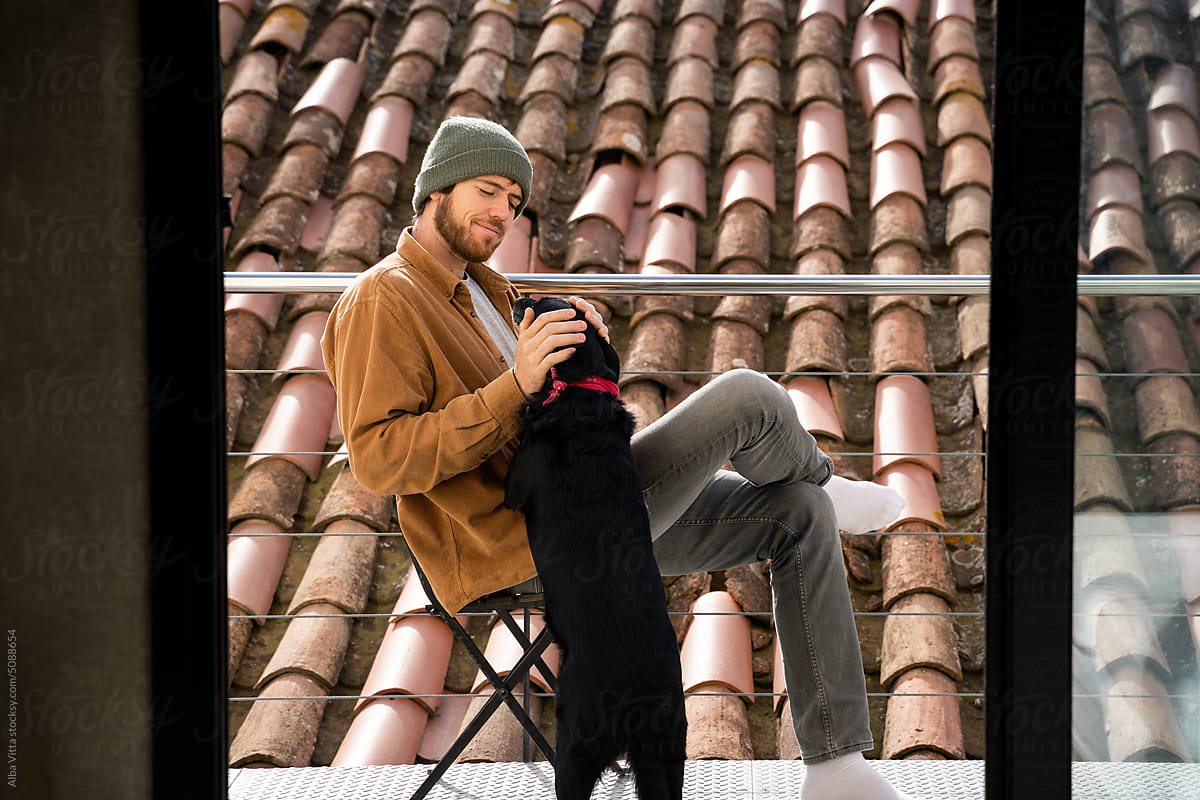 Man with dog relaxing on balcony