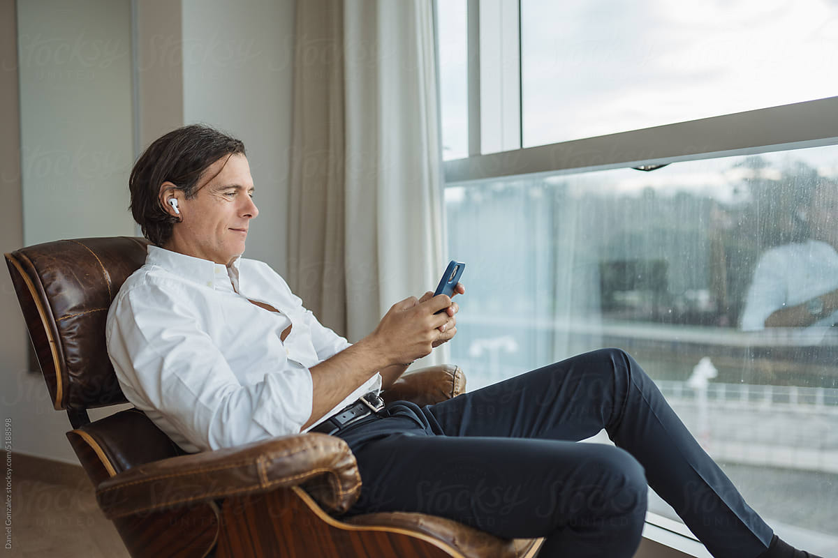 Mature businessman using smartphone near window