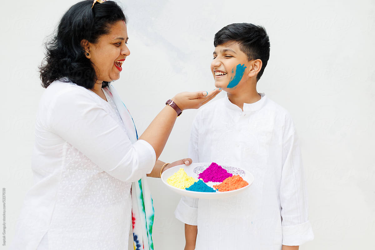 Mother playing holi with color powders with her son