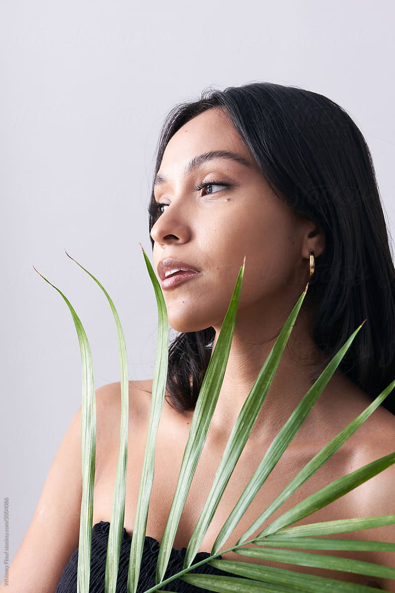Latina Woman Holding Majesty Palm Leaf to Her Face
