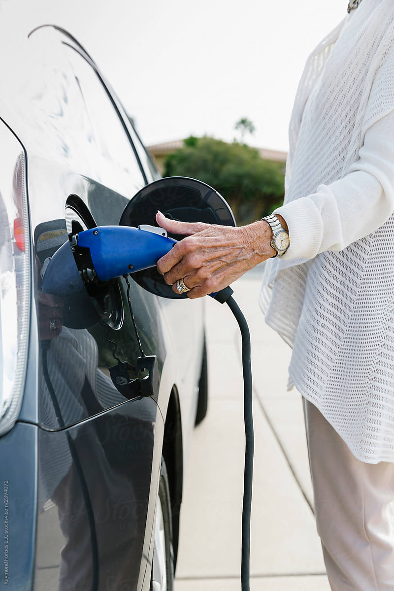 Senior Woman with Electric Car charging cord