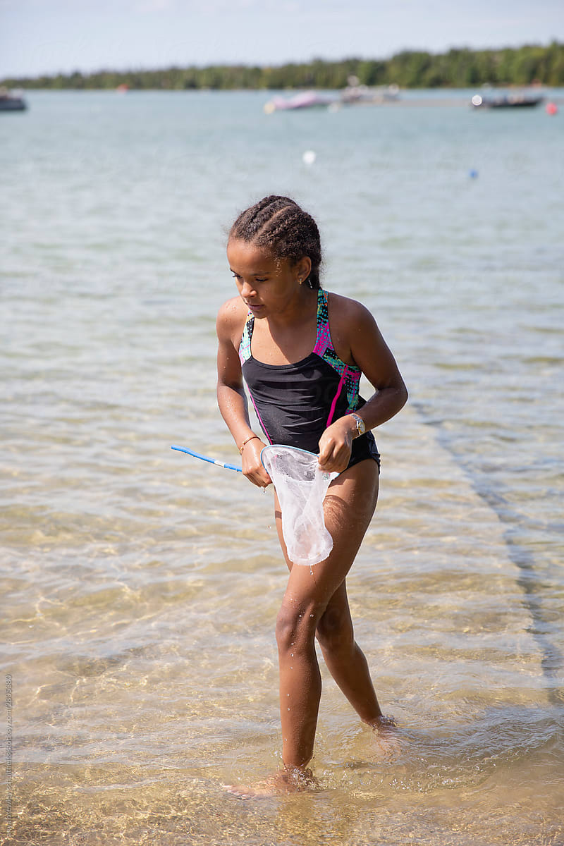Young Girl At A Beach Trying To Catch Fish In A Net by Stocksy