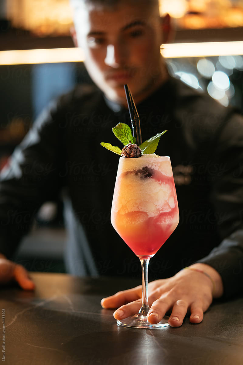 Bartender serving cocktail with cream and berries