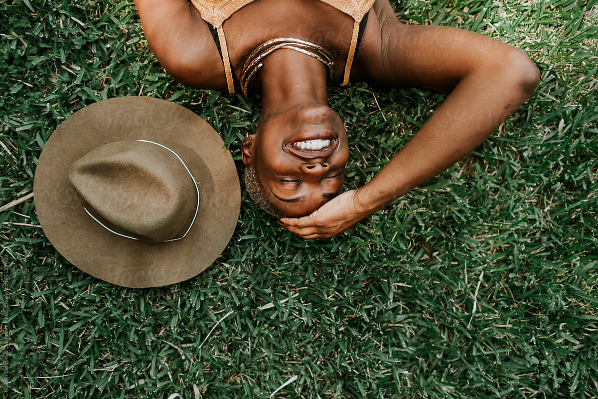 A Beautiful African American Woman Laying Down In A Bed Of Grass Del Colaborador De Stocksy