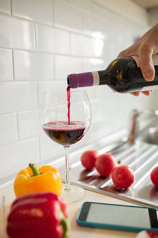 Man Pooring  a Red Wine Glass While is Cooking