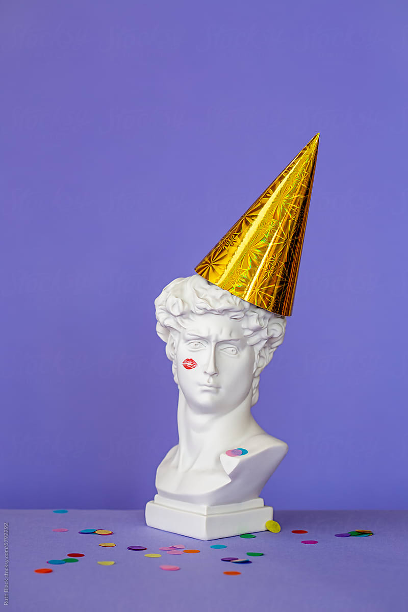 Male plaster bust with party hat and lipstick kiss