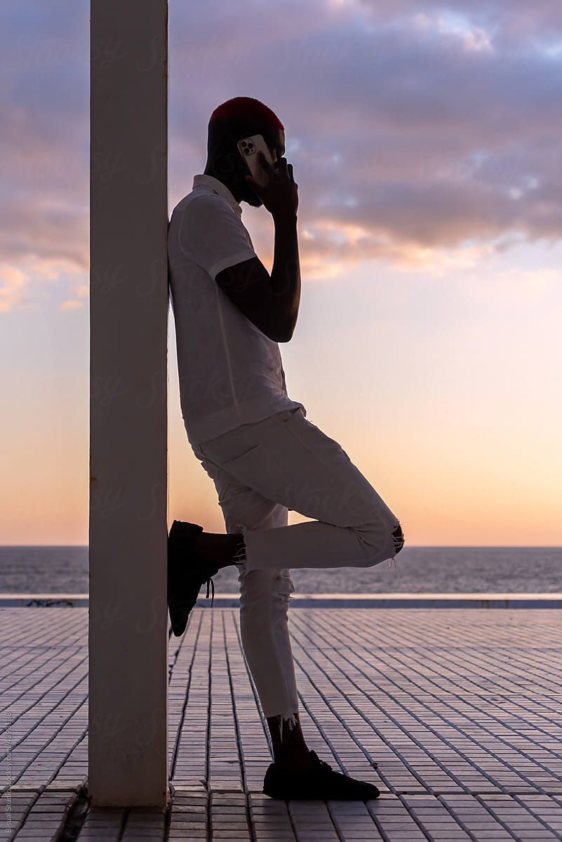 Black stylish man talking on the phone on sea embankment
