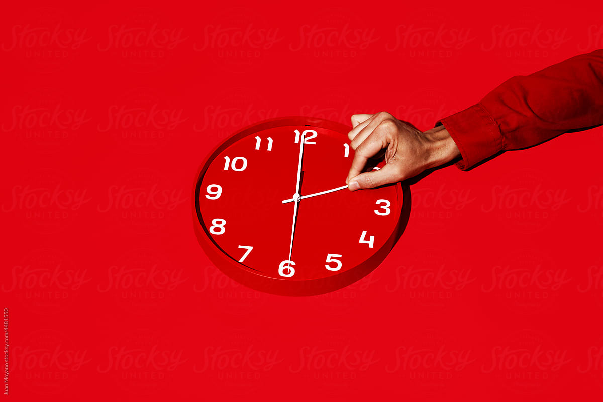 "man resets a red clock" by Stocksy Contributor "Juan Moyano"