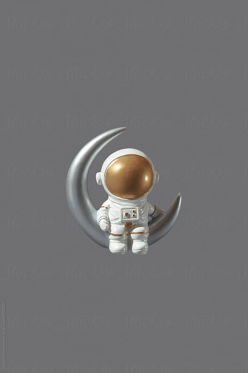 Toy astronaut sitting on sickle moon