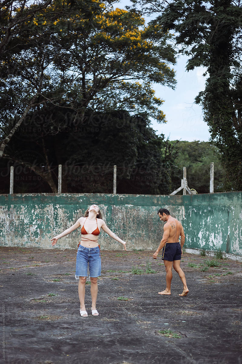 Woman and man walking in the tennis court surrounded by tropical sods