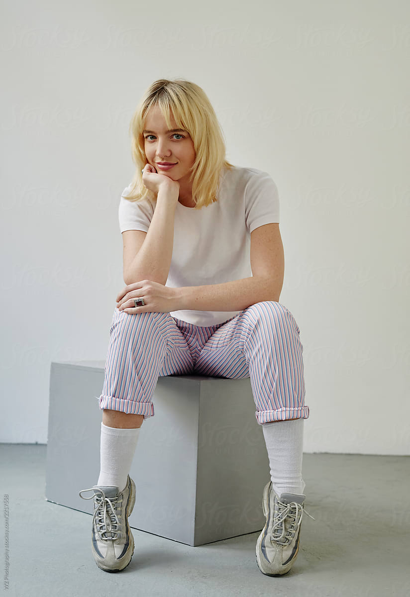 Portrait of a young blond sitting on a cube.