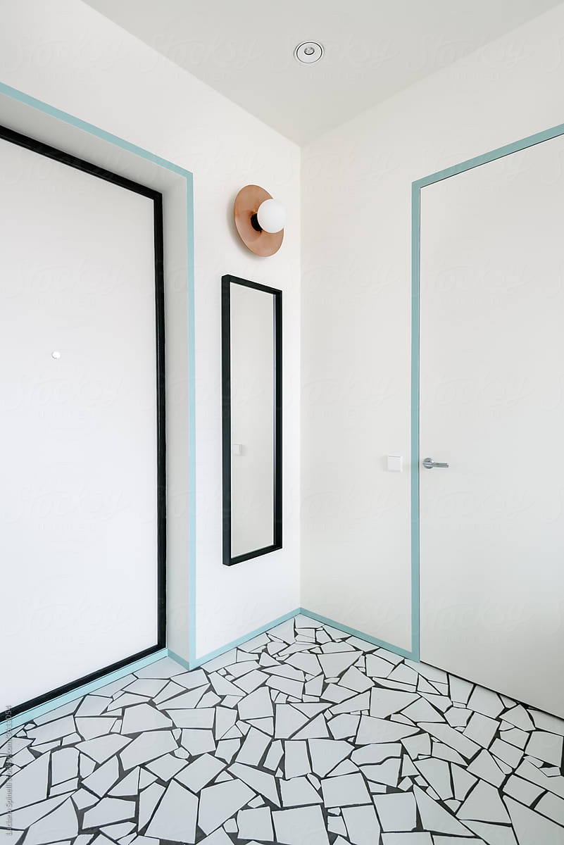Scandinavian style flat entrance hall with door, a circular lap on the wall and broken tiles style of floor