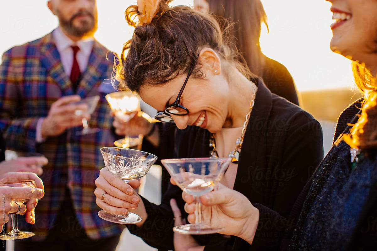 Crop smiling friends with alcoholic drinks during party in sunlight