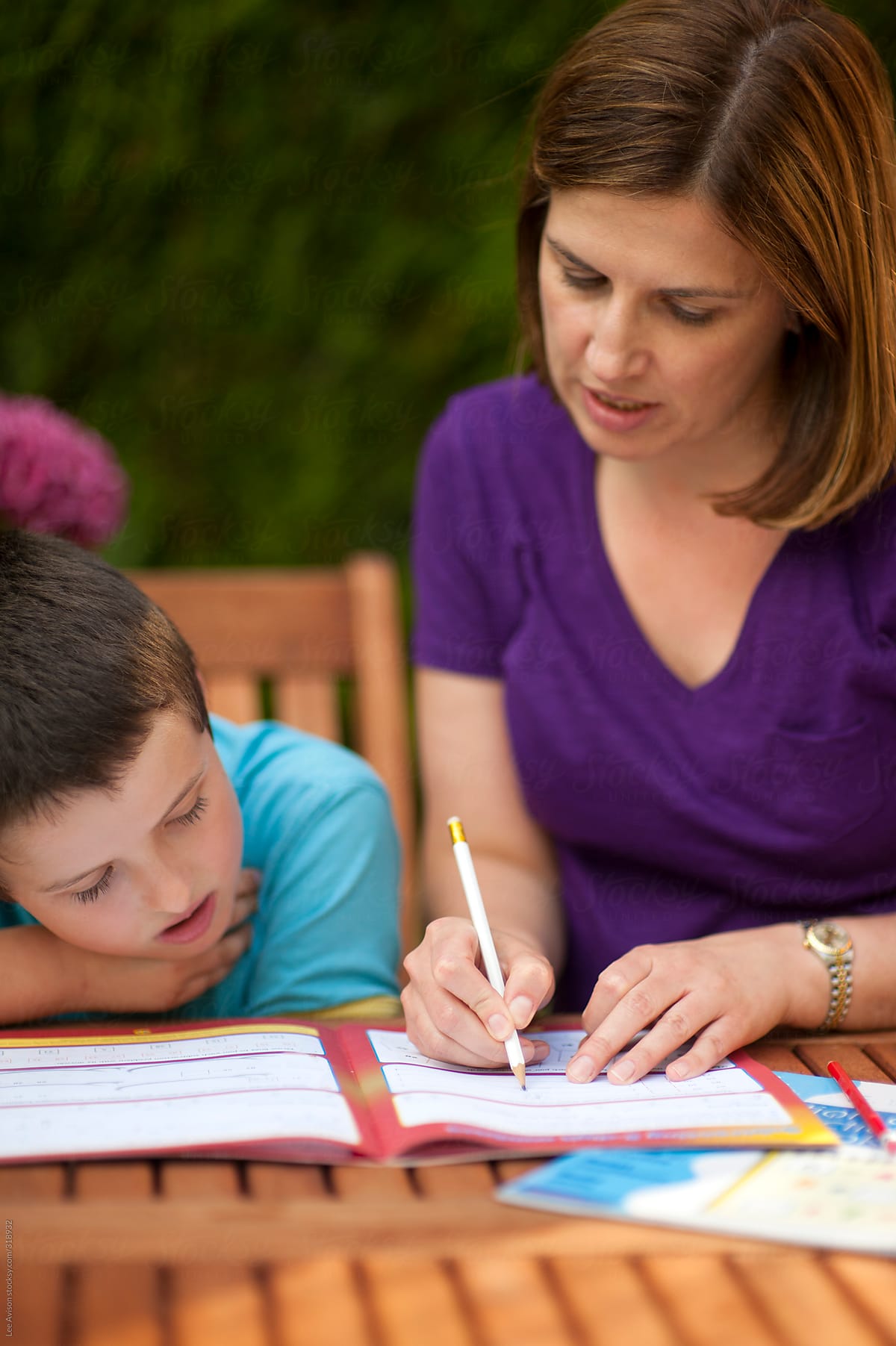 Mother Or Teacher Helping Her Son Or Pupil With School Work By