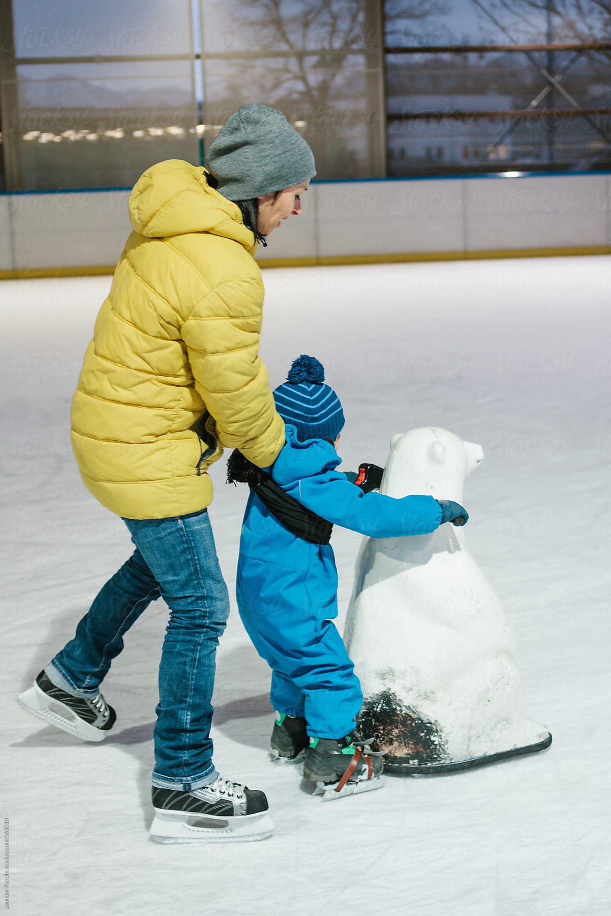 mother and son skating with a polar bear on ice rink