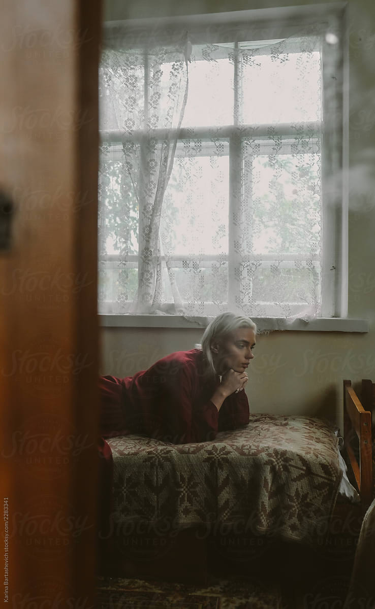 girl in a cherry dress is lying on the bed in the old room of the old Russian village