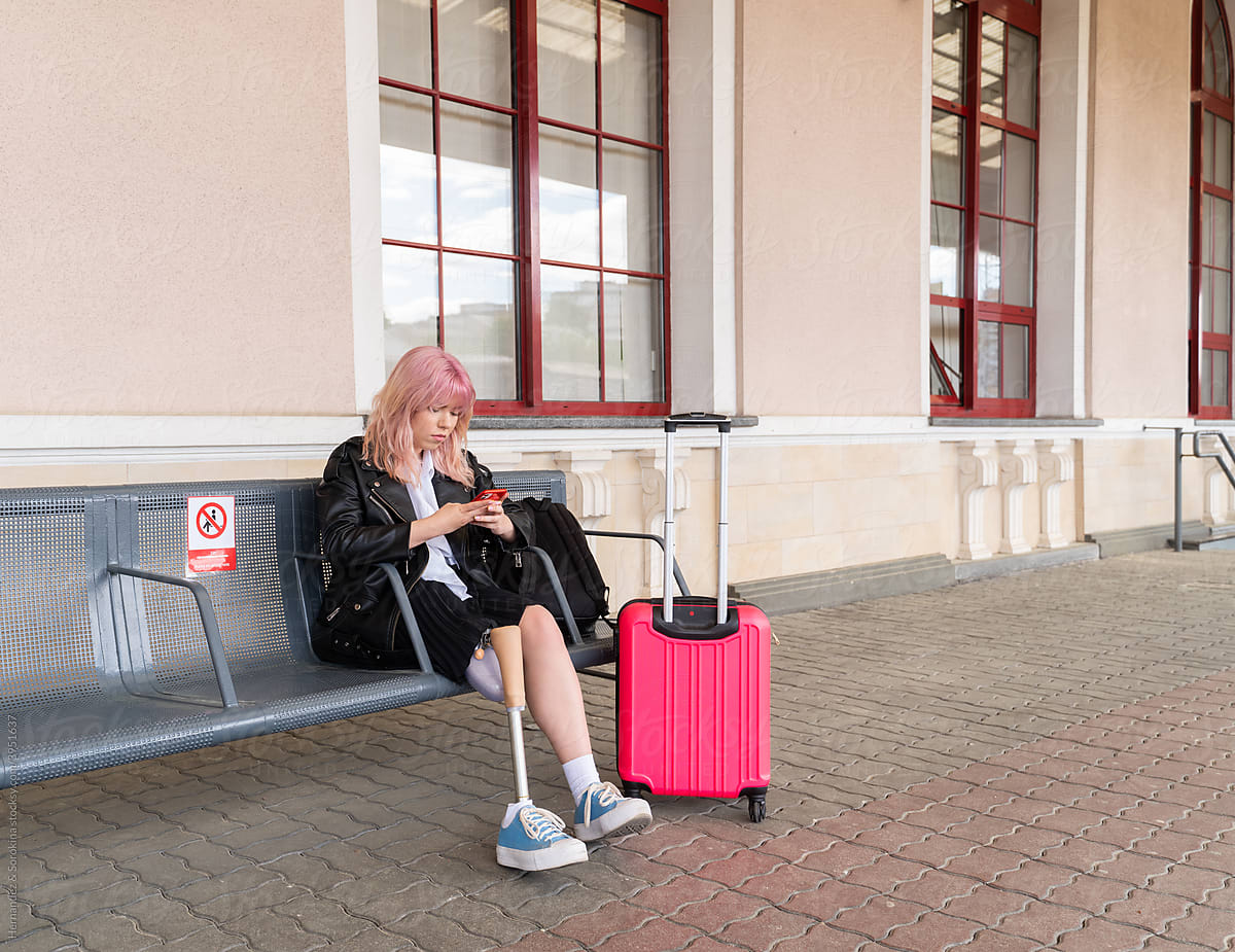 Female Traveler With Leg Prosthesis Using Mobile Phone