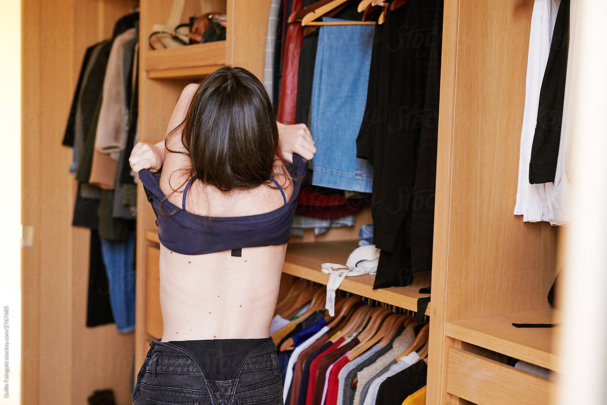 Girl taking off clothes near wardrobe