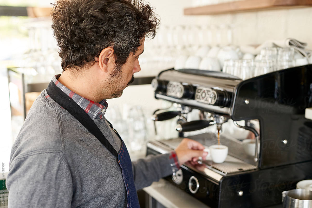 Barista making hot coffee in professional machine