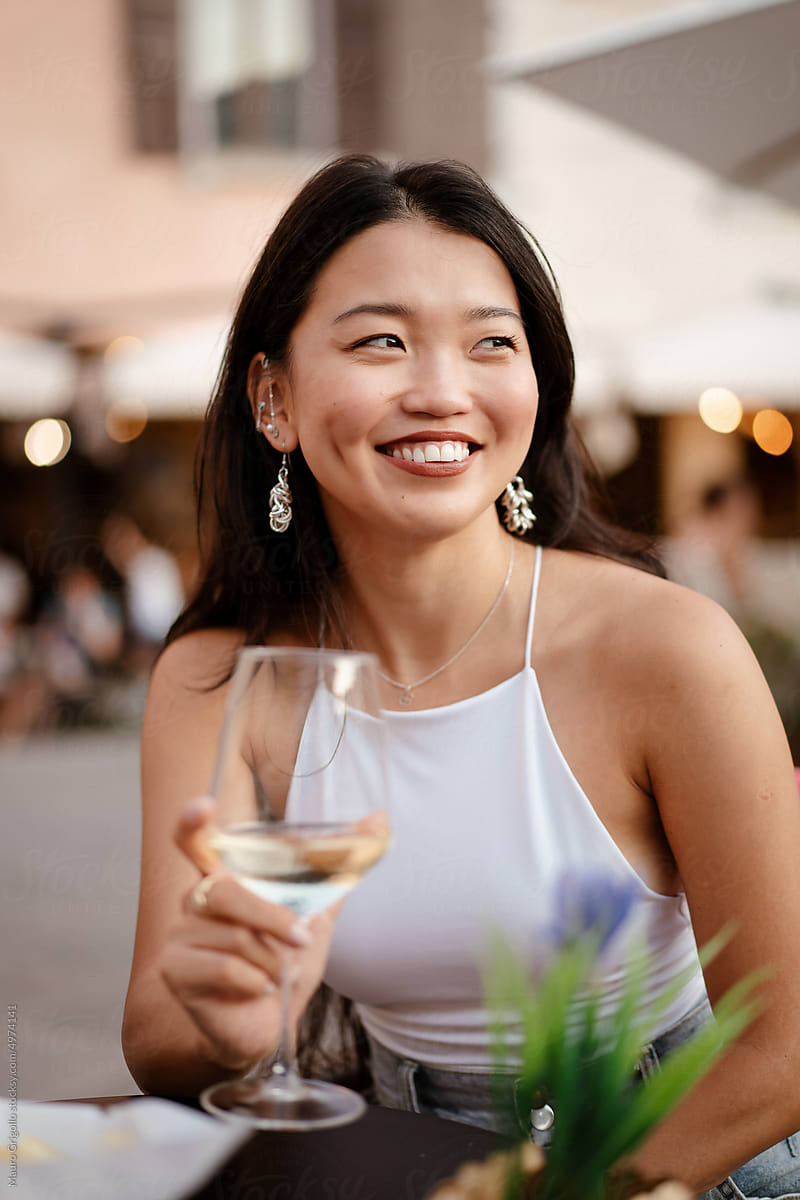 A smiling woman drinks wine at the bar and have fun