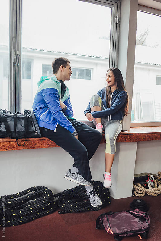 Man and Woman in Sportswear Sitting and Chatting in the Gym