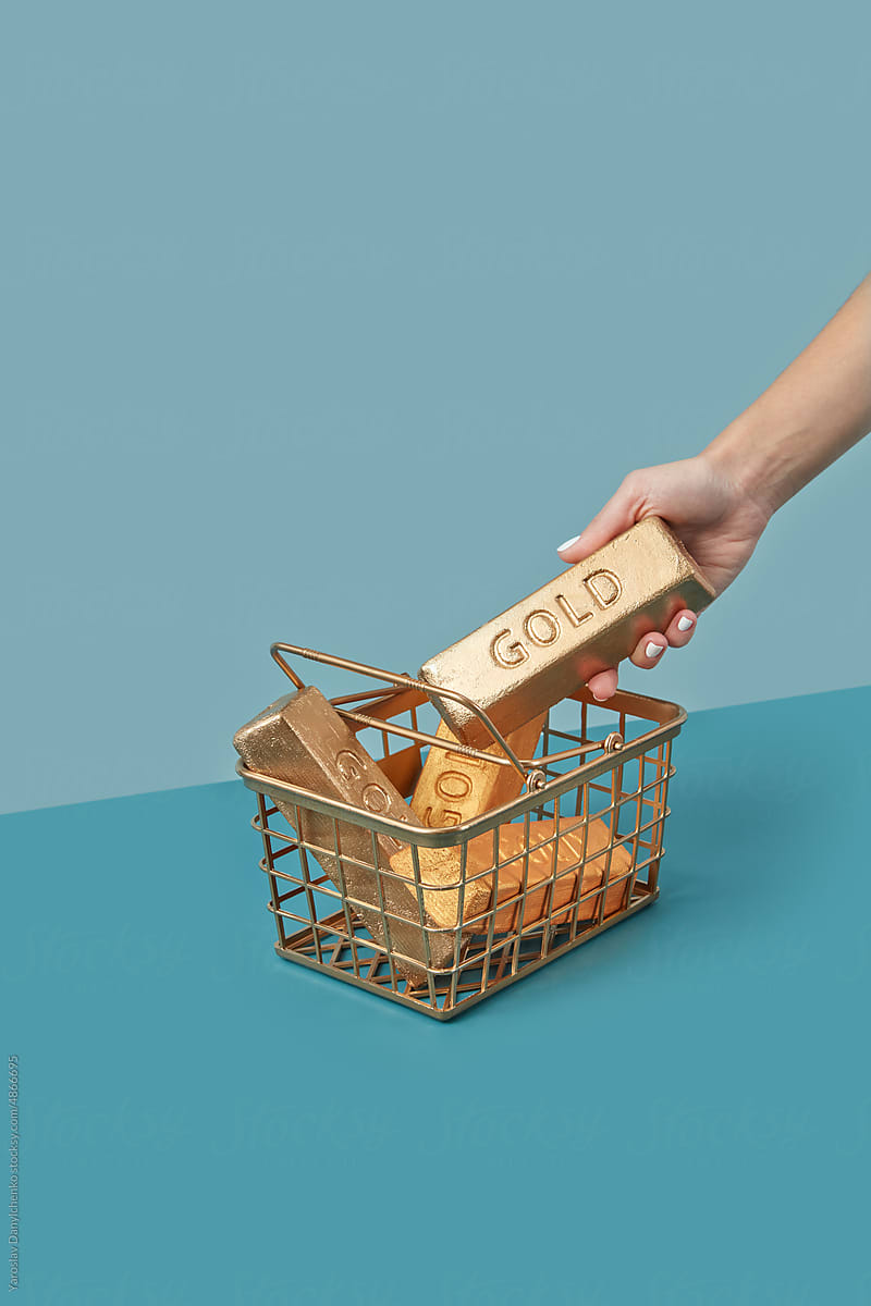Gold in gilded shopping basket taken by hand.