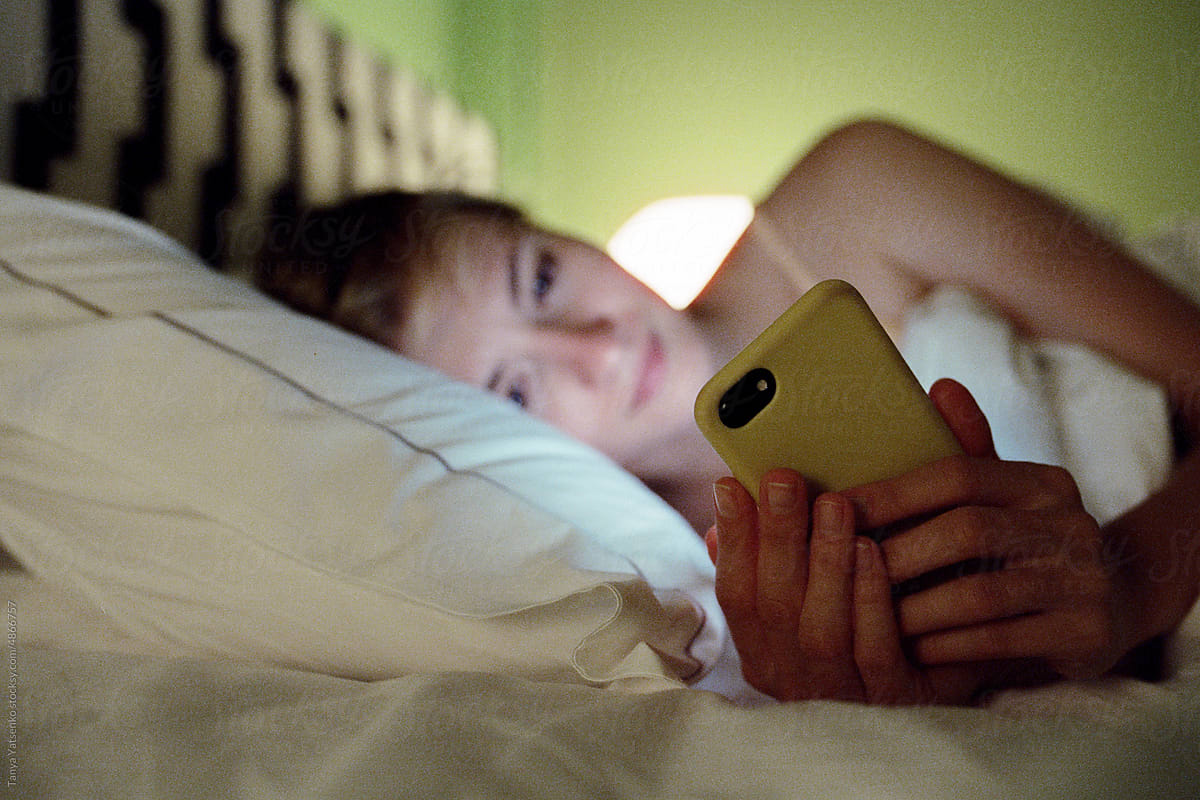 A woman with a mobile phone in bed