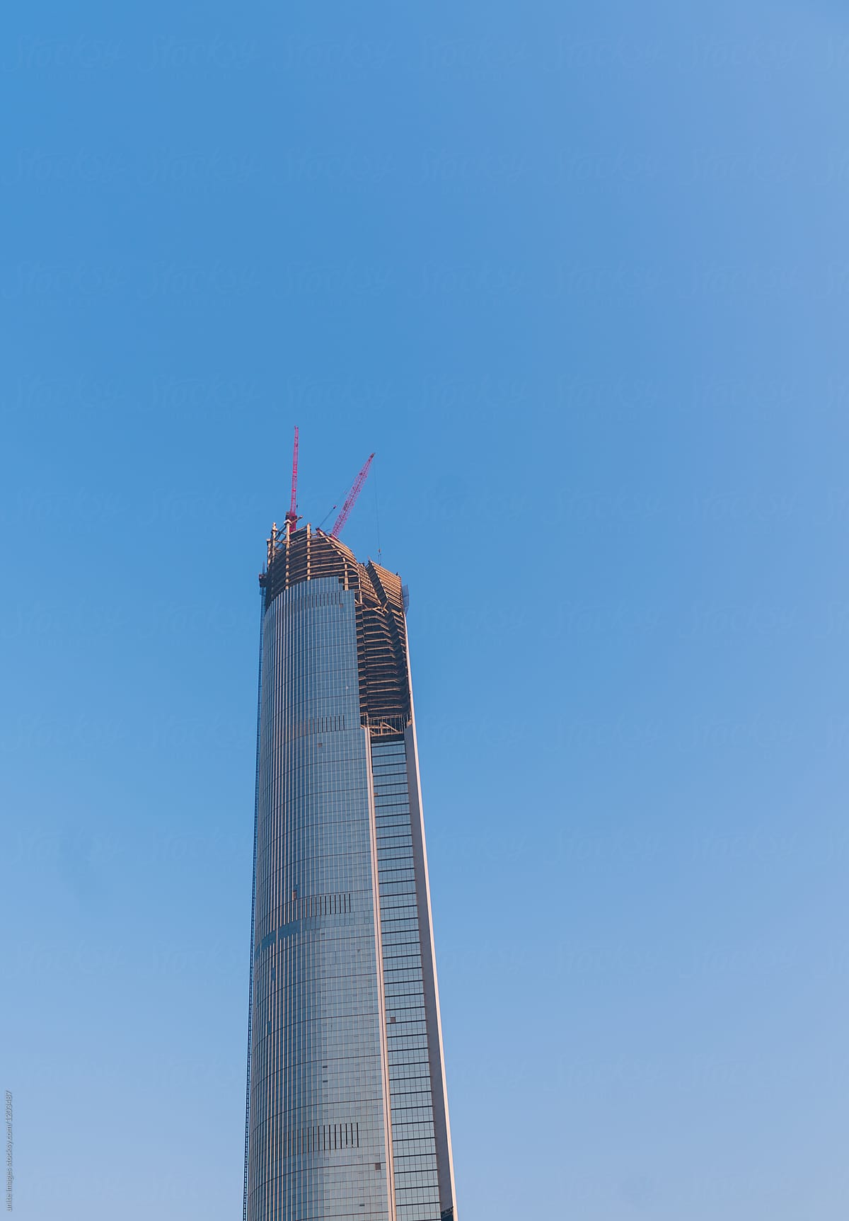 Crane and skyscraper construction site against blue sky