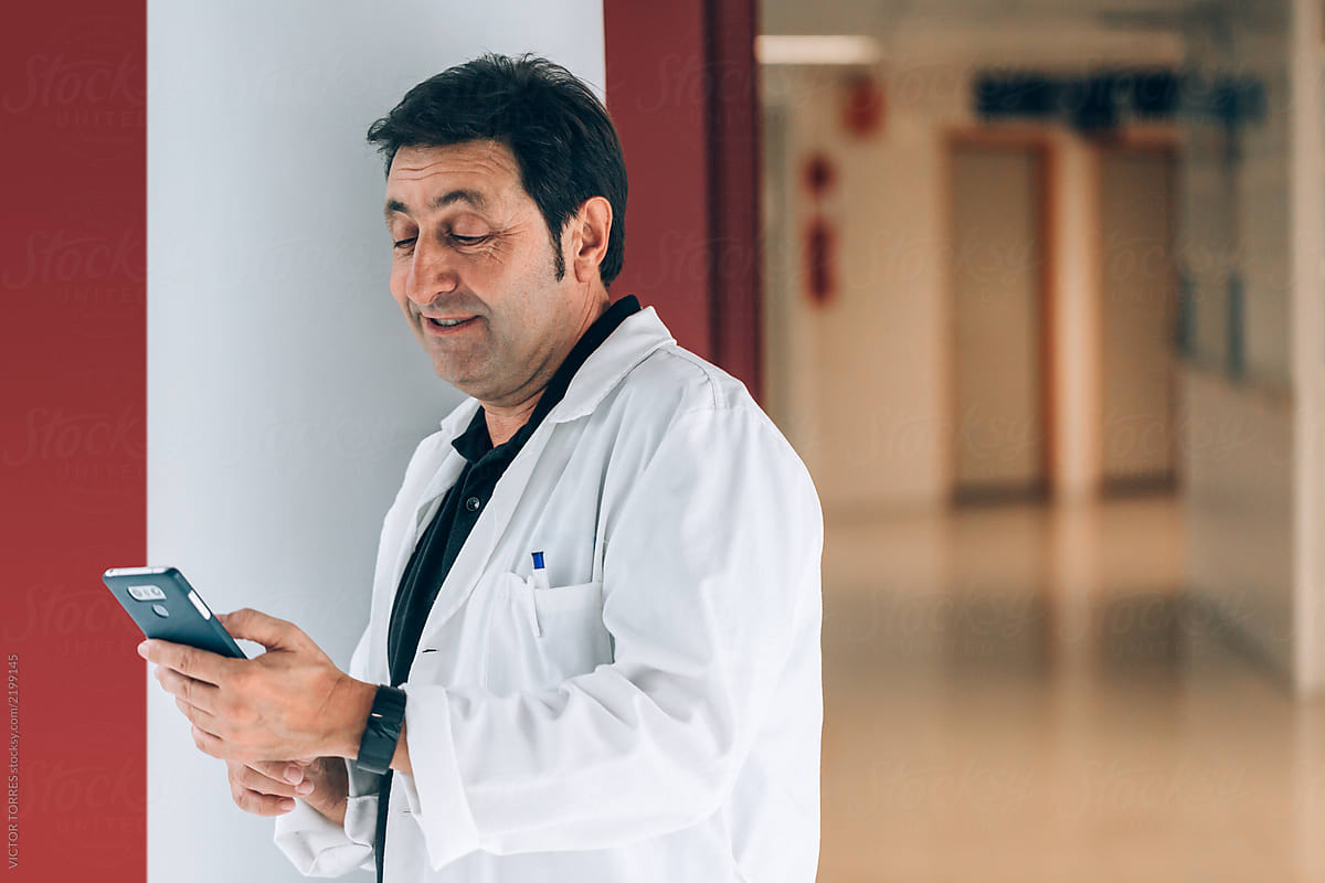  Doctor Using A Cellphone While Having A Break In The Hospital Corridor 
