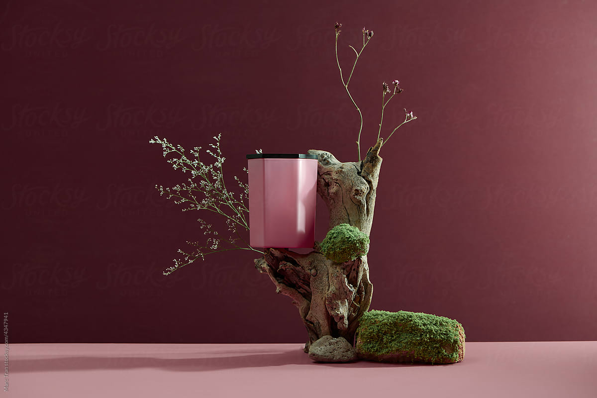 Candle on glass on a concrete stone with moss podium and wooden branch on brown background.